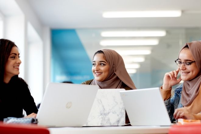 Female students sitting together with their laptops