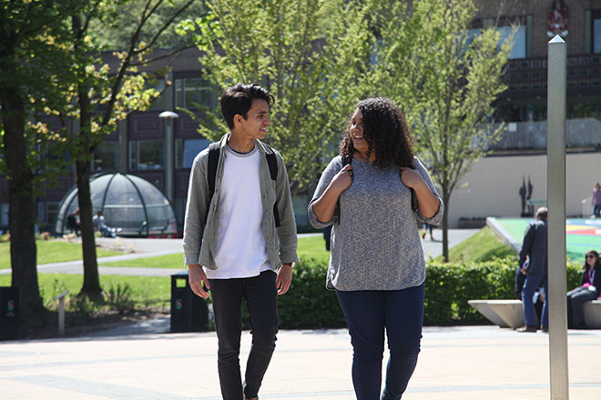 Two students chatting and walking through campus