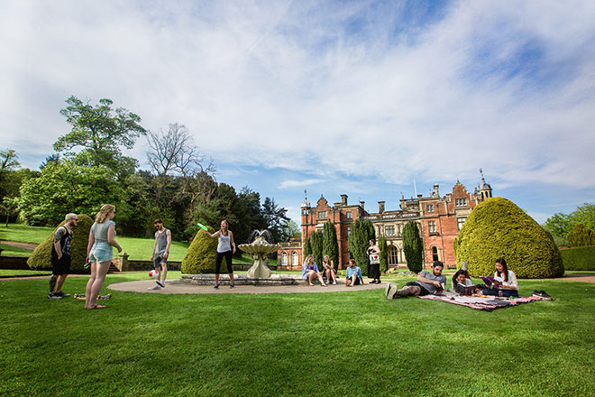 Students playing and relaxing on the grass outside Keele Hall